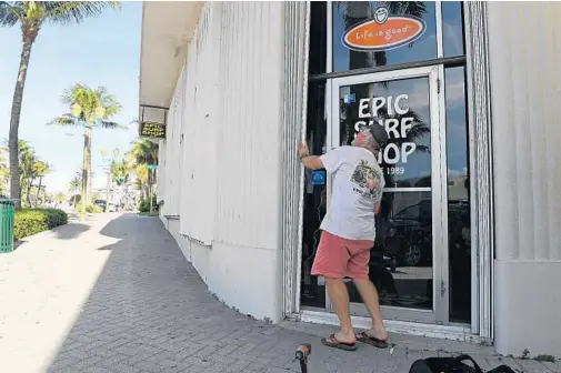  ?? JIM RASSOL/STAFF PHOTOGRAPH­ER ?? Walter Soltess prepares his surf shop on East Atlantic Avenue in Delray Beach for the arrival of Hurricane Irma, a scene seen throughout South Florida through Friday.