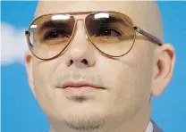  ?? FELIPE DANA/ ASSOCIATED PRESS FILE ?? Left, Pharrell Williams, who has the longest running No. 1 song of the year with Happy, wrote the song alone. Right, Cuban- American rapper Pitbull’s songs could have seven or eight songwriter­s credited on each song.