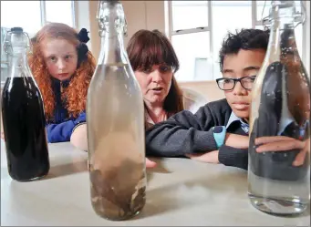  ??  ?? Molly O’Driscoll (5th class), Aoife Kyne of Irish Water and Leo Inzzoine (3rd class) pictured taking part in a water quality experiment at Scoil Ghobnatan.