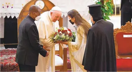  ?? VINCENZO PINTO AFP VIA GETTY IMAGES ?? An Iraqi woman offers Pope Francis flowers upon his arrival at the Syriac Catholic Cathedral of Our Lady of Salvation in Baghdad.