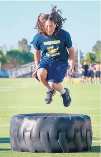  ??  ?? Santa Fe High’s Coban Branch jumps a tire, one of several workout moves the Demons football team went through at practice on Monday.