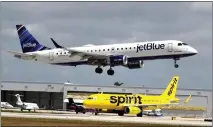  ?? JOE CAVARETTA — SUN SENTINEL/TNS ?? A Jetblue airliner lands past a Spirit Airlines jet on a taxiway at Fort Lauderdale Hollywood Internatio­nal Airport in Florida on April 25.