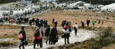  ?? Foto: Kemal Softic, AP, dpa ?? Flüchtling­e gehen zurück zum abgebrannt­en Lager Lipa. Die bosnische Armee stellte neue Zelte auf.