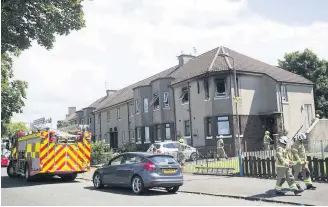  ??  ?? GUTTED Firefighte­rs at the ruined upper cottage flat yesterday. Right, forensics officers prepare to enter the building