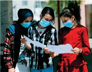  ?? AFP ?? Palestinia­n school girls wearing face masks view their end of year certificat­es upon receiving them at a school in Gaza City on Wednesday. Schools in Gaza were not able to carry on with the second (spring) academic term due to the onset of coronaviru­s pandemic. —