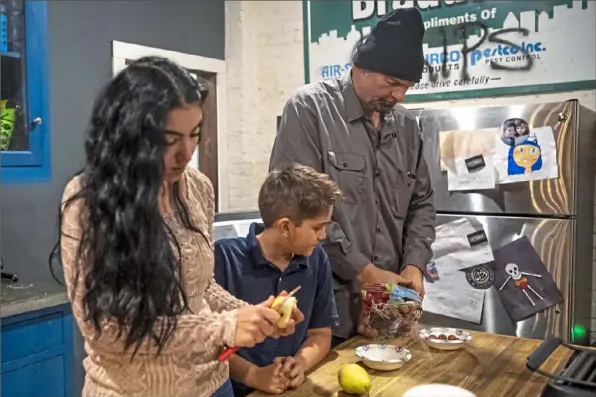  ?? Alexandra Wimley/Post-Gazette ?? The Fettermans, from left, Gisele, Karl, 9, and John prepare school lunches Dec. 12 at their home in Braddock.