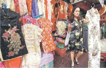  ??  ?? A Thai woman buy clothes to celebrate Chinese New Year in Chinatown in Bangkok, Thailand. — Reuters photo