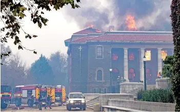  ?? — AFP photo ?? Firefighte­rs try, in vain, to extinguish a fire in the Jagger Library, at the University of Cape Town, after a forest fire came down the foothills of Table Mountain, setting university buildings alight.