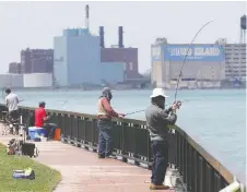  ??  ?? Anglers near the Ambassador Bridge in Windsor maintain their distance.