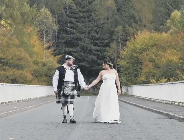  ??  ?? 0 Newlyweds Magdalena Gordon and Iain Gordon walk across Gordon Bridge at Linn of Tummel near Pitlochry