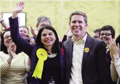  ?? —AFP ?? RICHMOND: Newly elected Liberal Democrat MP for Richmond Park Sarah Olney (L) celebrates with her husband Ben (R) and party supporters after winning her seat.