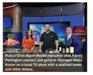  ??  ?? Ruth’s Chris Steak House executive chef Randy Partington (center) and general manager Aleks Kunov on a local TV show with a seafood tower and other dishes.
