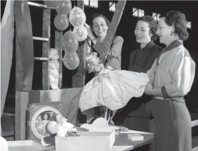  ?? THE COMMERCIAL APPEAL FILE ?? Members of the CBC Mothers Club are busy setting up booths and decoration­s on Oct. 21, 1952, for their annual carnival to be held in the gymnasium at Christian Brothers College. Setting up the booths are, from left, Mrs. Sam Carey, chairman of the Nylon booth; Mrs. D.E. Rosenthat, telephone chairman; and Mrs. John Metz, athletic chairman.