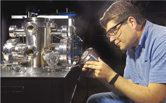  ?? COURTESY OF DINO VOURNAS/ SANDIA LABS ?? Sandia National Laboratori­es researcher Nils Hansen, assembling equipment in the Combustion Research Facility, says new insights on how to control the chemistry of ignition behavior and pollutant formation will lead to the design of new fuels and improved combustion strategies.