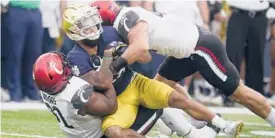  ?? DARRON CUMMINGS/AP ?? Notre Dame’s Kyren Williams (23) is tackled by Cincinnati’s Curtis Brooks, bottom, and Joel Dublanko during Saturday’s game in South Bend, Ind.