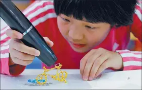  ??  ?? A young visitor to the expo plays with a pen that can create 3-D artworks.