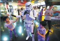  ?? HE HAIER/FOR CHINA DAILY ?? A man dressed up as a robot plays around with two kids at a Wanda cinema in Qingdao, Shandong province.