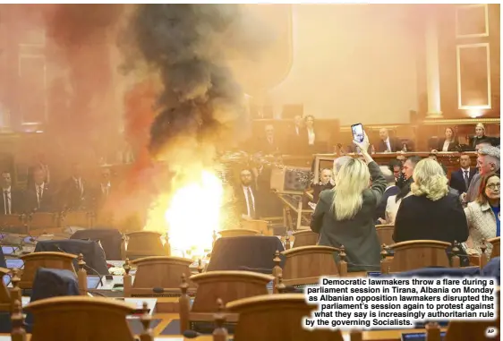  ?? AP ?? Democratic lawmakers throw a flare during a parliament session in Tirana, Albania on Monday as Albanian opposition lawmakers disrupted the parliament’s session again to protest against what they say is increasing­ly authoritar­ian rule by the governing Socialists.