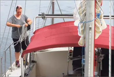  ?? Christian Abraham / Hearst Connecticu­t Media ?? Ivy Spillman stows a line while hanging out on a yacht she gets to use at Harbor Point Marina in Stamford on Friday. The region will be bracing for Hurricane Henri, which is expected to hit Connecticu­t over the weekend causing coastal flooding and wind gusts up to 60 mph.