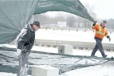  ?? JASON BAIN/EXAMINER ?? Allan Carruthers and Fred Sharpe of Encore Tents fold a tarp in Ashburnham Memorial Park below Peterborou­gh Lock 21 following the Under the Lock hockey tournament on Monday. A freezing rain warning for Tuesday afternoon and night is in effect for...