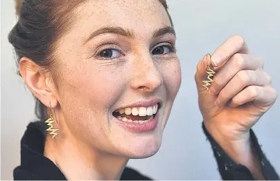  ?? PHOTO: PETER MCINTOSH ?? Golden opportunit­y . . . Otago Polytechni­c student Alesha Pyers poses with the diamondstu­dded gold heartbeat earrings she designed, which will be auctioned for charity later this month.