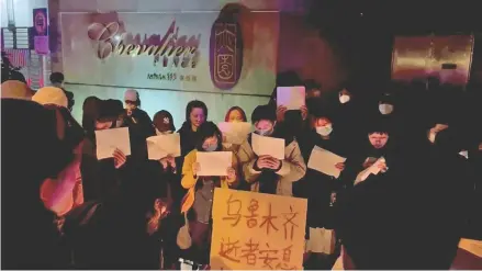  ?? Photo: Reuters ?? People hold signs during a candleligh­t vigil held for the victims of the Urumqi fire, in Shanghai, China on November 26, 2022 in this picture obtained from a social media video.