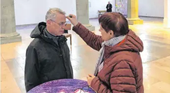  ?? FOTO: WAGGERSHAU­SER/DIÖZESE ROTTENBURG-STUTTGART ?? Ralf Reiter lässt sich in seiner Mittagspau­se das Aschekreuz auf die Stirn zeichnen und freut sich, dass er die kirchliche Tradition trotz Berufsallt­ag miterleben kann.