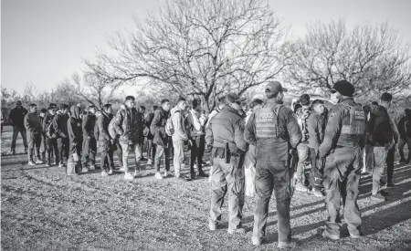  ?? SERGIO FLORES AFP/Getty Images/TNS ?? After crossing the river illegally near the highway outside Eagle Pass, Texas, a group of migrants is processed by Border Patrol agents Feb. 4.