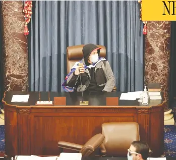  ?? WIN MCNAMEE / GETTY IMAGES ?? An insurgent sits in the Senate Chamber in Washington on Wednesday after angry supporters of President
Donald Trump stormed the U.S. Capitol during a joint session, smashing windows and looting offices.