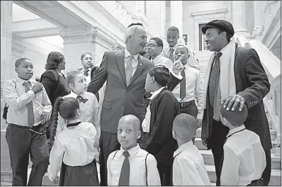 ?? Arkansas Democrat-Gazette/THOMAS METTHE ?? Arkansas Gov. Asa Hutchinson (center) talks to pastor Aaron Agnew, director of Word of Outreach Christian Academy, after posing for a photo with academy students Wednesday during the School Choice Rally at the Capitol.