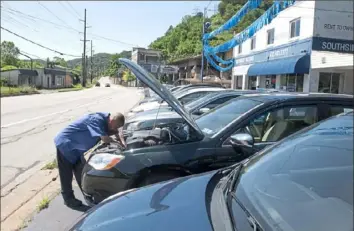  ?? Pittsburgh Post-Gazette ?? Chuckie Jarrett, a mechanic at South Side Motors, a used car dealership, checks under the hood of a vehicle June 17 on the South Side. Computer chip shortages are affecting car dealership­s small and large as people hesitate to trade in their vehicles.