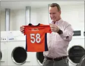  ?? BEN SWANSON — DENVER BRONCOS VIA AP ?? During filming for the Denver Broncos’ 2021schedu­le release video, former QB and current “intern” Peyton Manning washes a Von Miller jersey at UC Health Training Center.