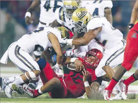  ?? Robert Gauthier Los Angeles Times ?? STAYING ON TOP OF THE SITUATION, UCLA defenders swarm over Arizona quarterbac­k Anu Solomon (12) during the second quarter. Solomon, who suffered what was reported to be a possible head injury on the play, left the game and didn’t return.