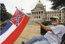  ?? Rogelio V. Solis / Associated Press ?? Larry Eubanks waves Mississipp­i’s flag outside the Capitol in Jackson. He wants voters to decide on its final design.