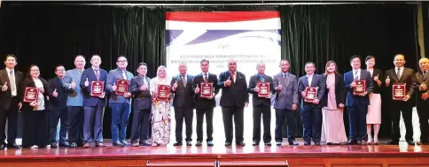  ??  ?? (From 11th left) Ahmad Kamarulnaj­uib and Amirul join other MoU signatorie­s in a group photo on stage.