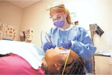  ?? STEFANY ZAMORA / MILWAUKEE JOURNAL SENTINEL ?? Lindsey Moelter, a dental hygienist at Columbia St. Mary's Family Health Center, 1121 E. North Ave., gives a preventive teeth cleaning and assessment to Shundle Porter at the center on Thursday. A new state law allows dental hygienists to work in...