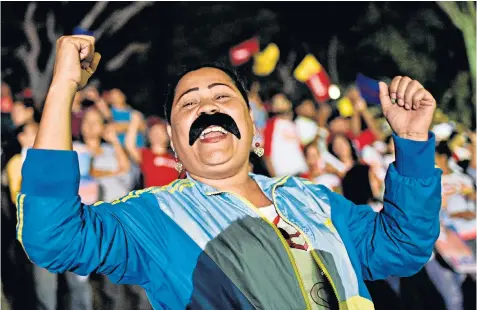  ??  ?? A woman sporting a Maduro moustache leads the celebratio­ns by pro-government supporters in Caracas after the president’s victory was announced