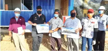  ??  ?? Awang Tengah (second left) and Henry Sum (third right) hold brochures showing an artist’s impression of the project.