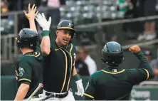  ?? Carlos Avila Gonzalez / The Chronicle ?? Frank Schwindel highfives teammates after blasting a tworun homer in the second inning at the Coliseum.