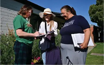  ?? ?? Volunteer canvassers Liz Grumbach (C) and Patricia Jones meet Lucy Meyer (L) who signs a petition outside her home in Phoenix, Arizona as the volunteers go door-to-door for signatures to get the petition for the Arizona Abortion Access act onto the November 2024 ballot for voters to decide.