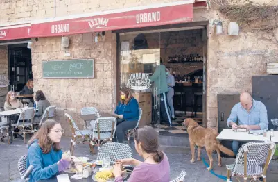  ?? ARIEL SCHALIT/AP ?? Diners eat March 7 at a Tel Aviv restaurant as restrictio­ns are eased after months of shutdowns imposed by Israel.