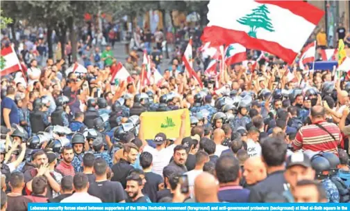  ??  ?? Lebanese security forces stand between supporters of the Shiite Hezbollah movement (foreground) and anti-government protesters (background) at Riad al-Solh square in the capital Beirut on Friday. — AFP