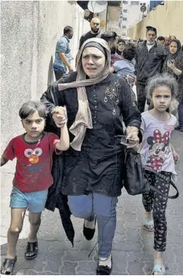  ?? Mahmud Hams / AFP ?? Famílies palestines evacuen desesperad­es un edifici atacat pel bombardeig israelià a la Gaza.