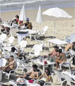  ?? Hannah McKay / Reuters ?? Diverses persones a la platja de Tel Aviv, hores després de l’atac.