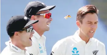  ??  ?? A butterfly flies past Trent Boult of New Zealand (R) after he bowled out Alastair Cook of England during the first day of the day-night Test at Eden Park in Auckland. — AFP