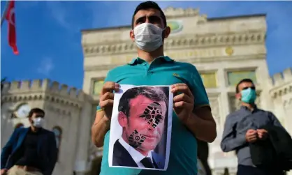  ??  ?? A protester in Istanbul holds a picture of Emmanuel Macron, which has been defaced with a shoe print Photograph: Yasin Akgül/AFP/ Getty