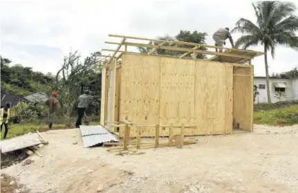  ??  ?? Workmen erecting a work shed at Perthland Drive in Mandeville.