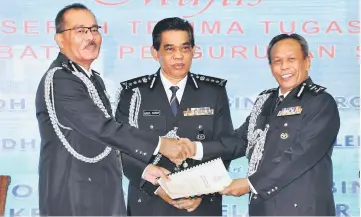  ??  ?? Abdul Samah (centre) witnessing the handing over of duties by SAC Che Man Mohd Dros (left) to SAC Sulaiman Salleh at the Selangor police contingent headquarte­rs. — Bernama photo