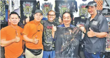  ??  ?? Wong (second right) is all smiles as he tries on the size of a T-Shirt while Razz Chopper Motor Club (RCMC) president Abd Razak Abd Salam (right) and committee members look on.