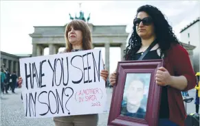  ?? (Christian Mang/Reuters) ?? TWO WOMEN hold up signs during a protest organized by Syrian activists in Berlin on Saturday calling for the release of political detainees after an amnesty decree by Syrian President Bashar Assad.